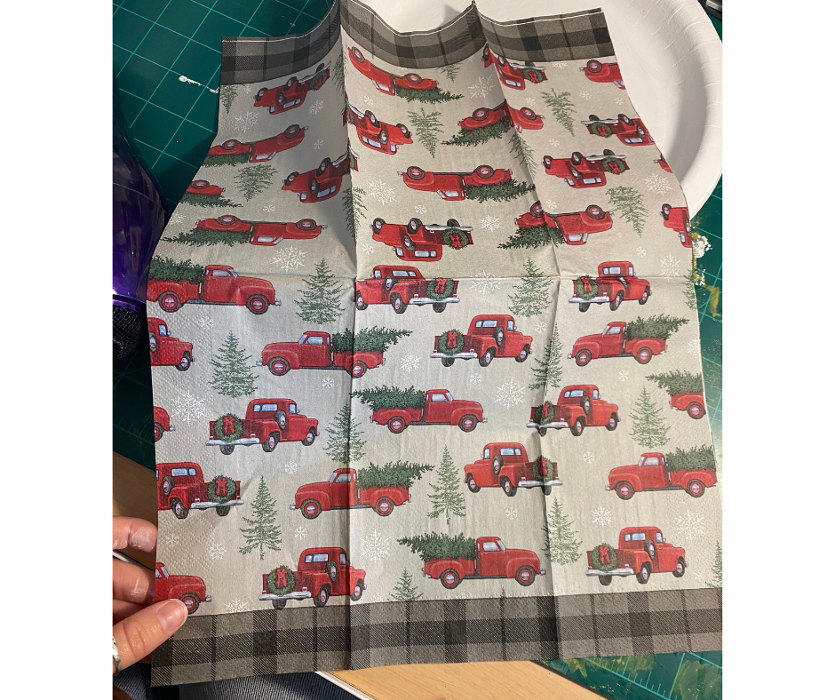 unfolded Christmas napkin with red trucks on it