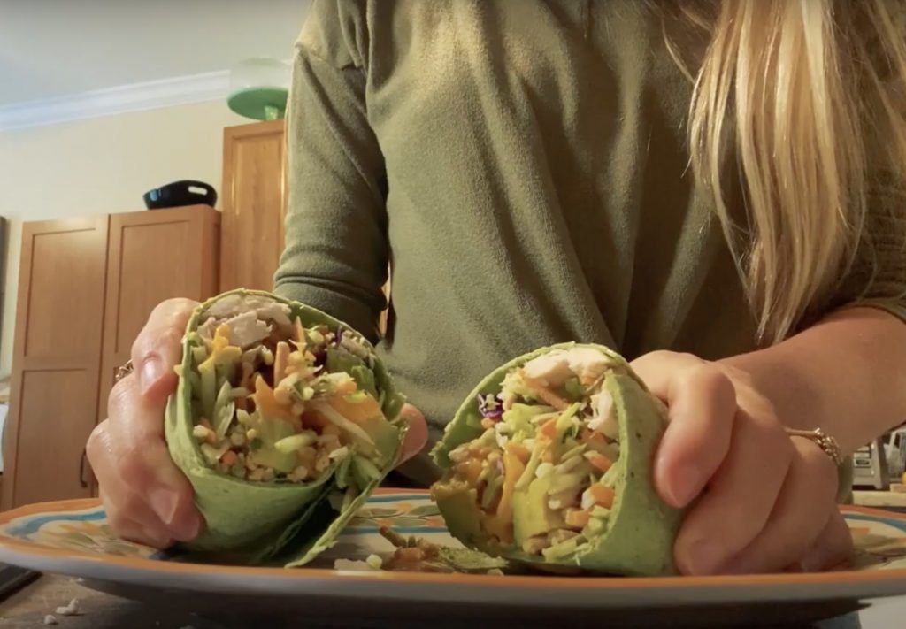 girl holding two halves of a chicken wrap