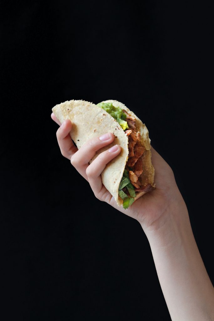 hand holding taco on black background